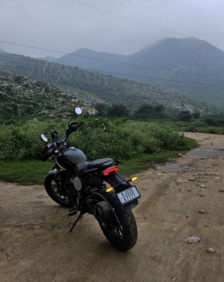 Triumph Scrambler 400X motorcycle on an off-road trail with mountain backdrop